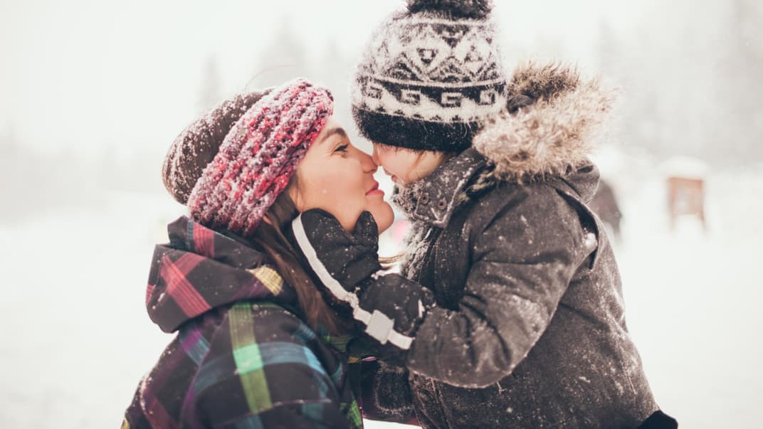 Mama und Kind Nase an Nase im Schnee.