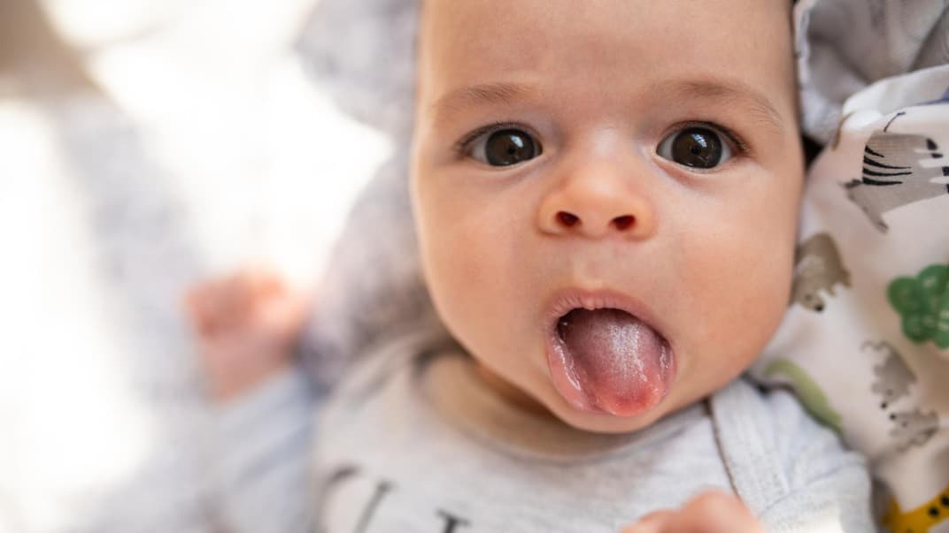 Ein kleines Baby streckt seine Zunge raus.