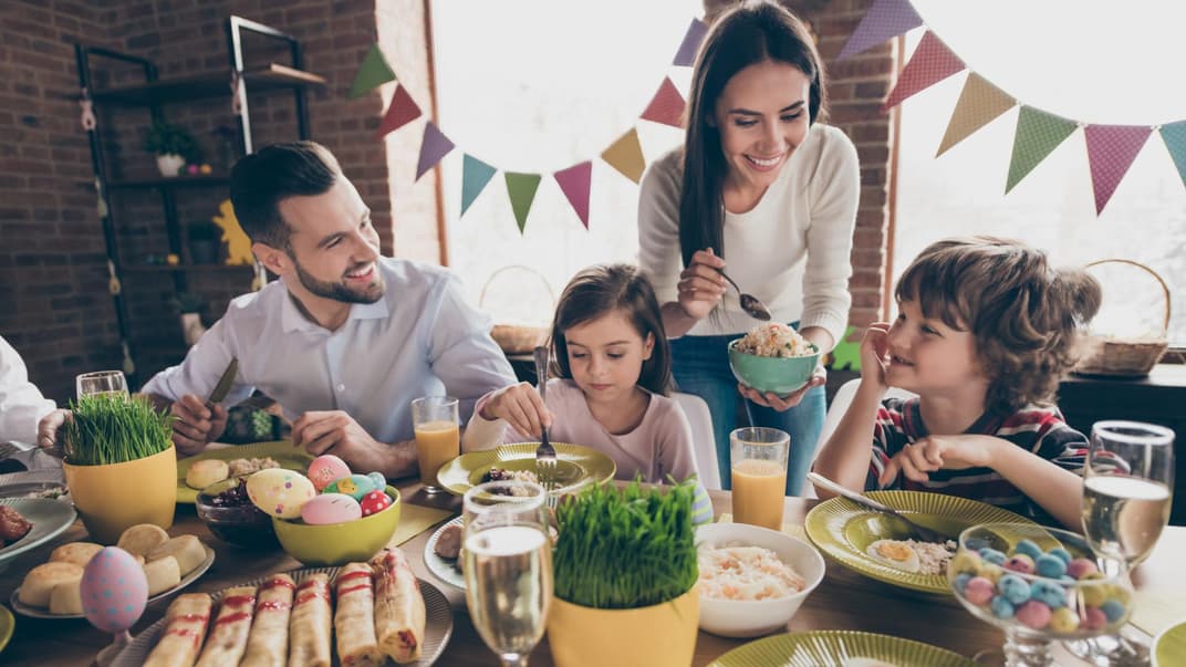 Es gibt viele Ideen für ein Osterfrühstück mit Kindern. Vater und Mutter genießen ihr Osterfrühstück mit ihrer Tochter und ihrem Sohn.