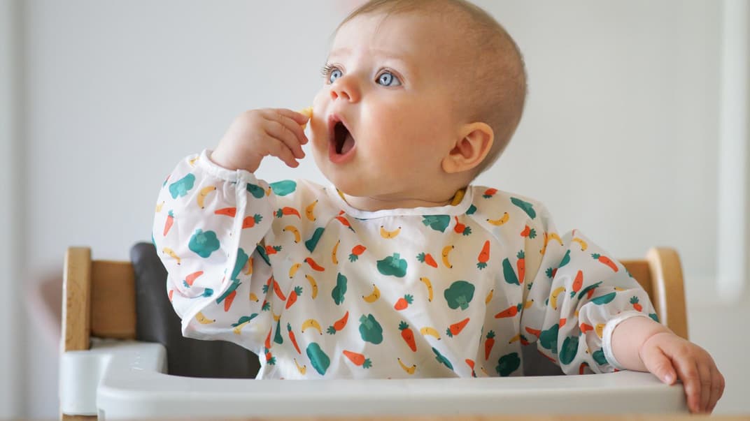 Baby steckt sich etwas zu Essen in den Mund. Baby steckt sich etwas zu Essen in den Mund.