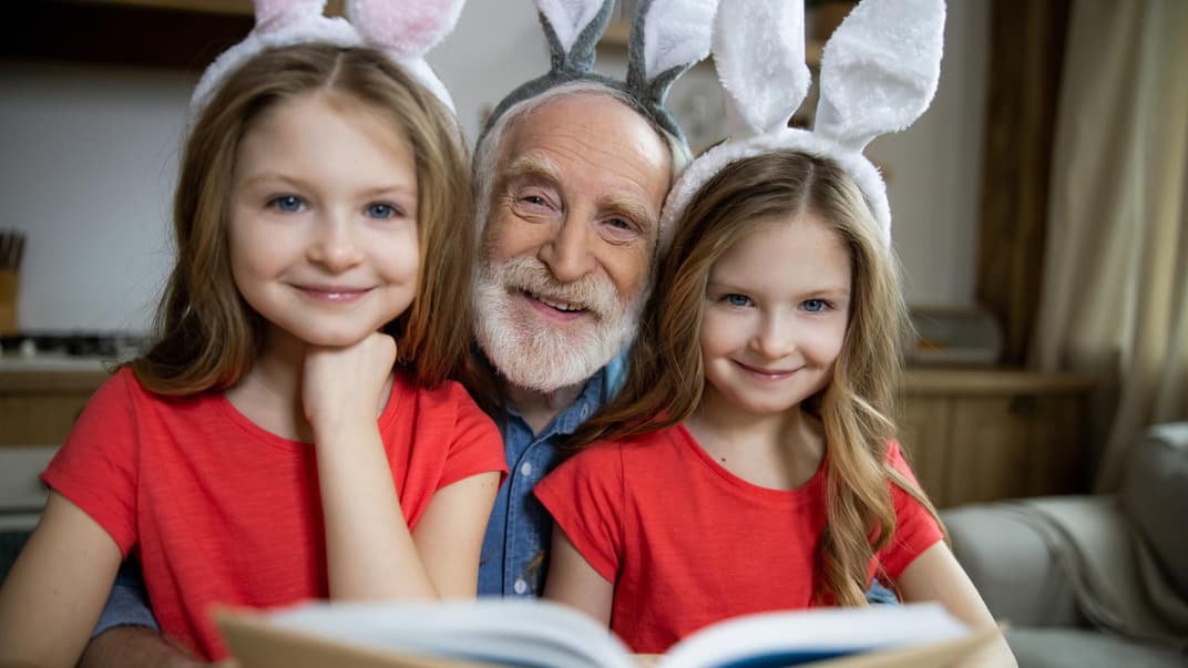 Opa liest seinen beiden Enkeltöchtern aus einem Osterbuch vor. 