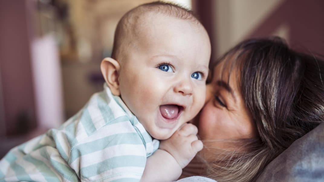 Mama küsst ihr lachendes Baby