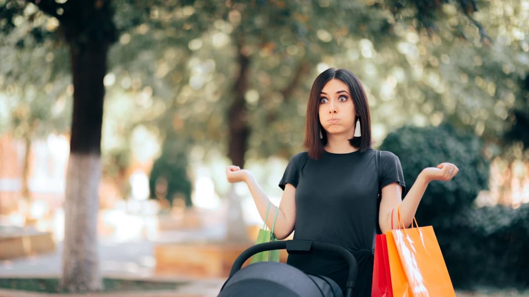 Genervte Frau mit Kinderwagen und Einkaufstüten