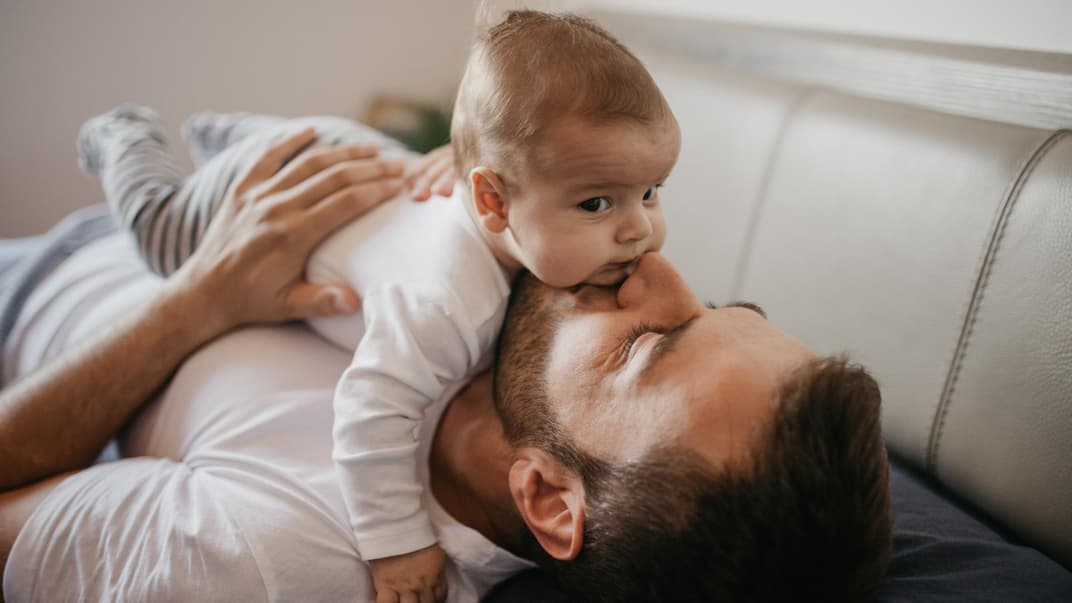Ein Baby liegt auf dem Bauch seines Vaters.