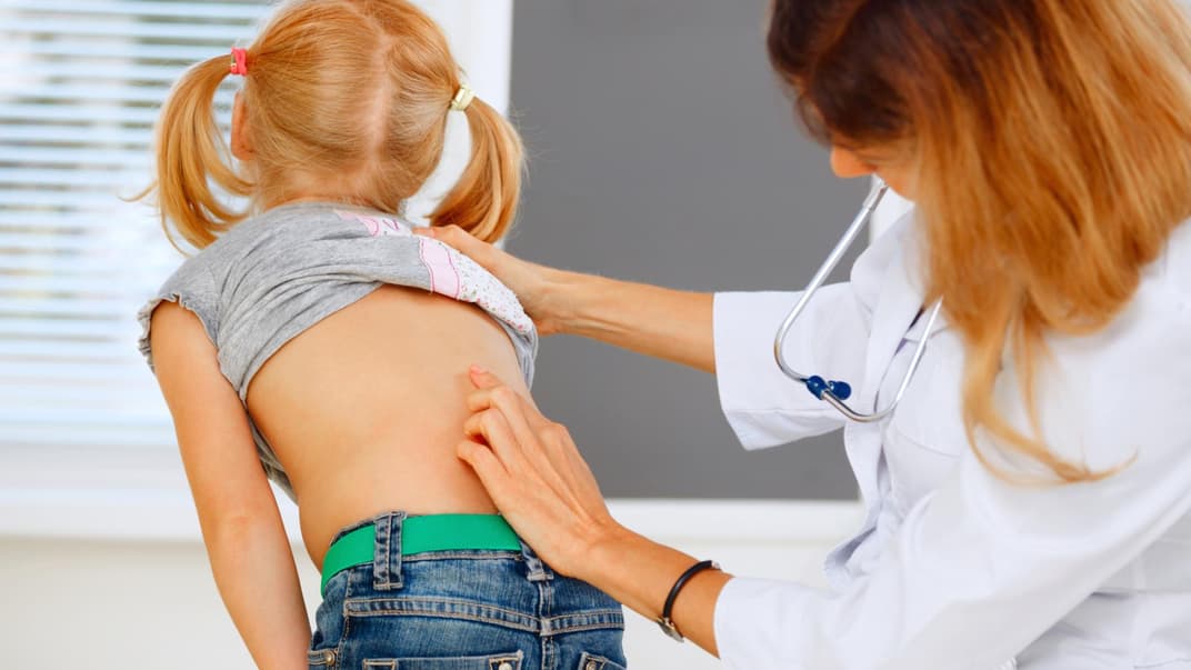 Ärztin untersucht den Rücken eines Mädchens