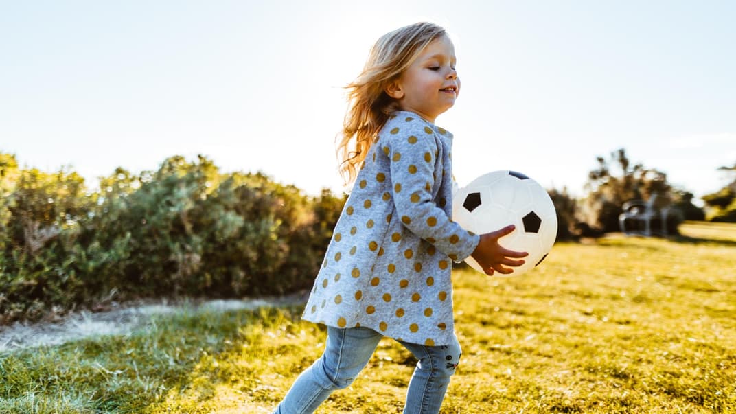 Ein Mädchen spielt mit einem Ball.