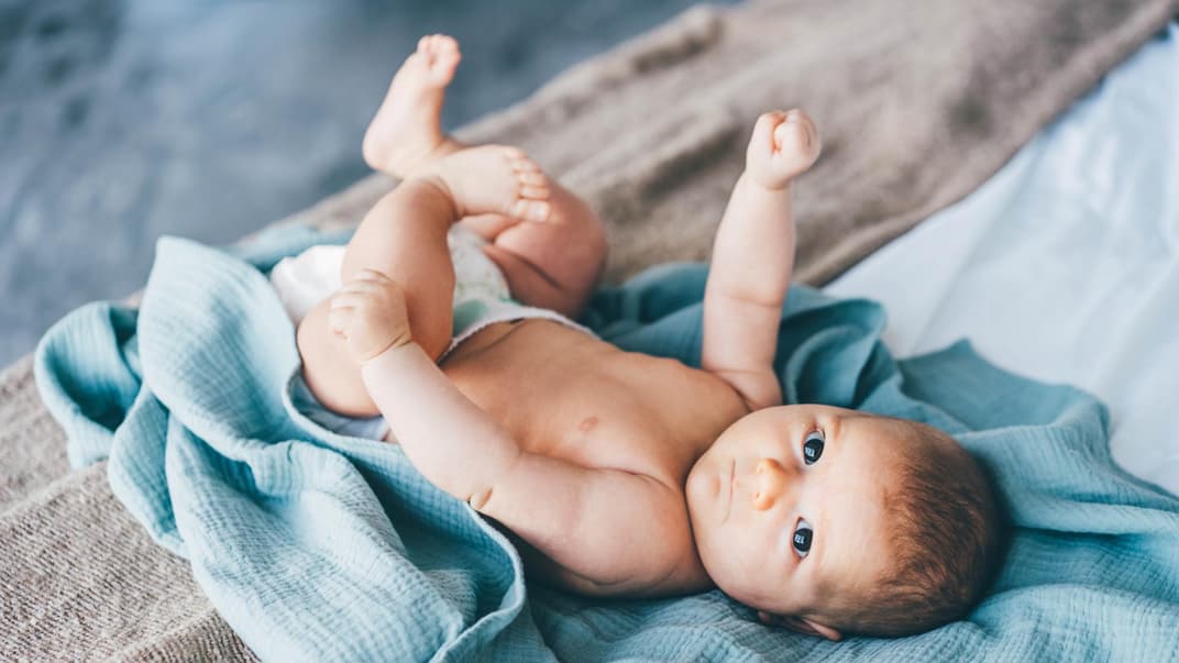 Ein Baby liegt auf einem blauen Tuch.