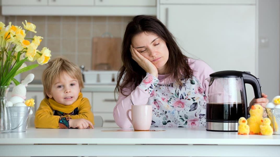 Mama sitzt müde am Tisch, Kind ist hellwach