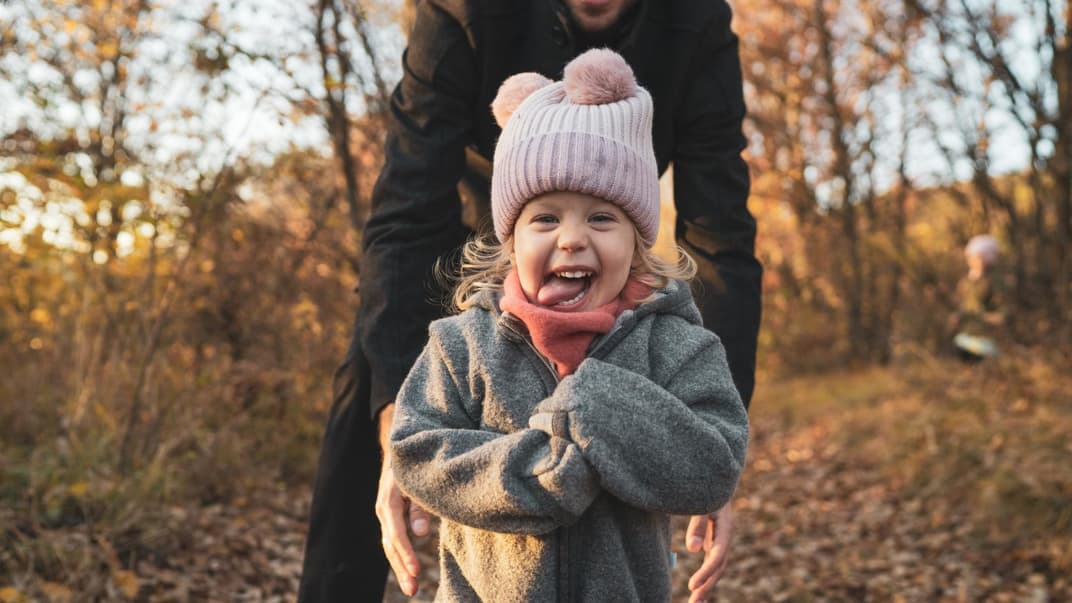 Ein Mädchen spielt glücklich im Laub.