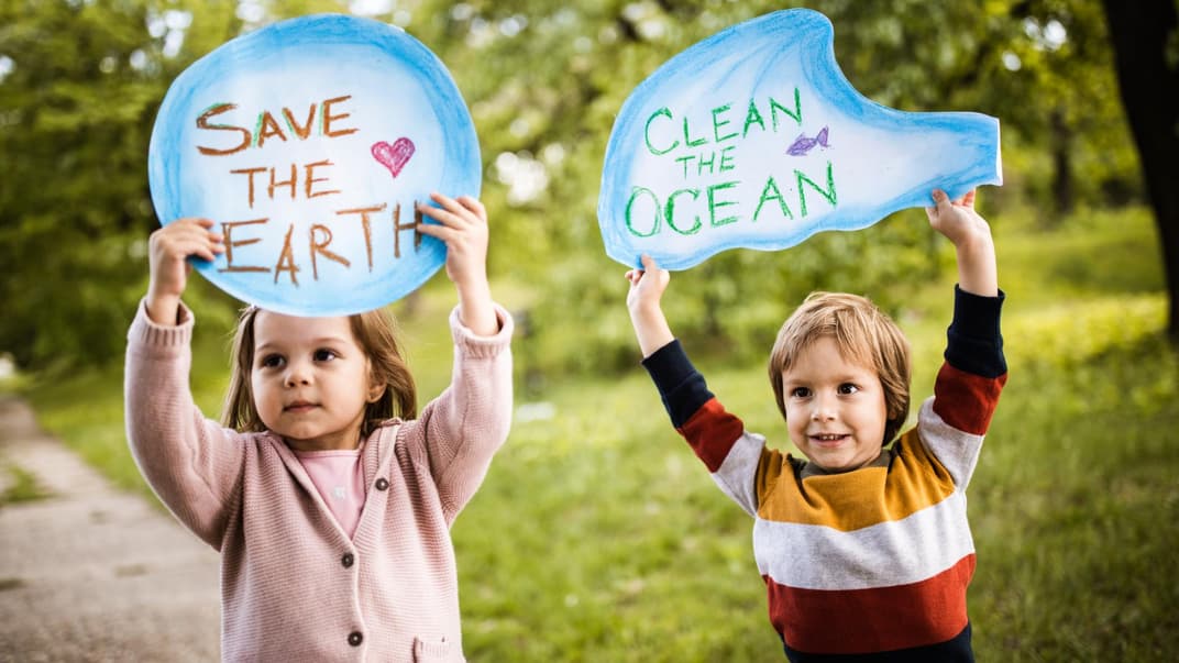 Ein Mädchen und ein Junge halten Schilder mit der Aufschrift "Save the Earth" und "Clean the Ocean".