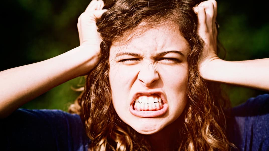 Wütende Frau rauft sich die Haare.