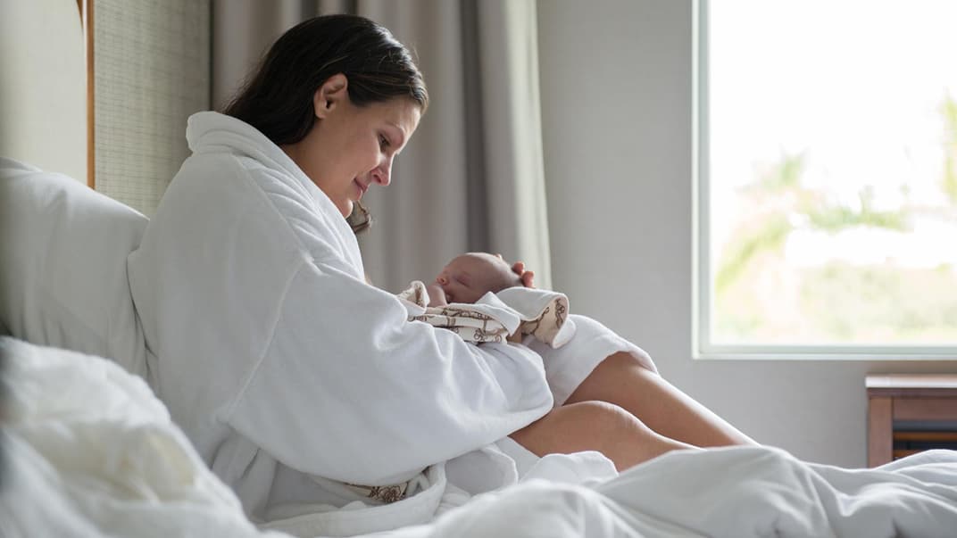 Junge Mama hält ihr Neugeborenes