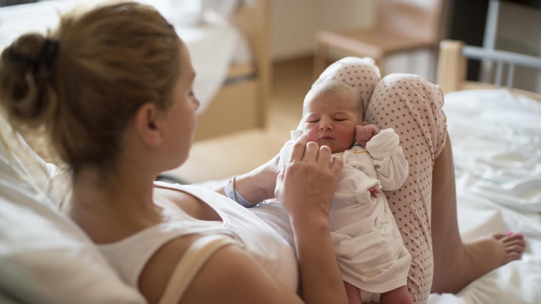 Eine junge Mama hält ihr Neugeborenes.