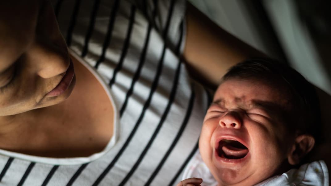 Mutter hält ihr schreiendes Baby im Arm.