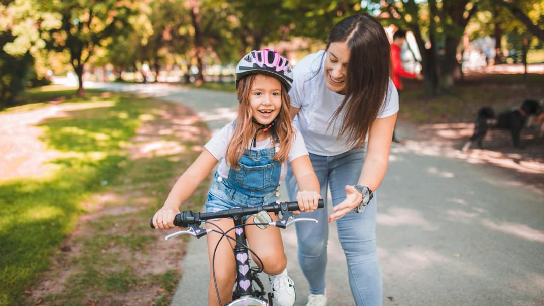Mama bringt Tochter Fahrradfahren bei