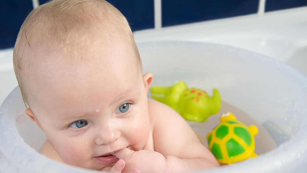 Kleiner Baby-Junge badet im Badeeimer nach Anleitung.