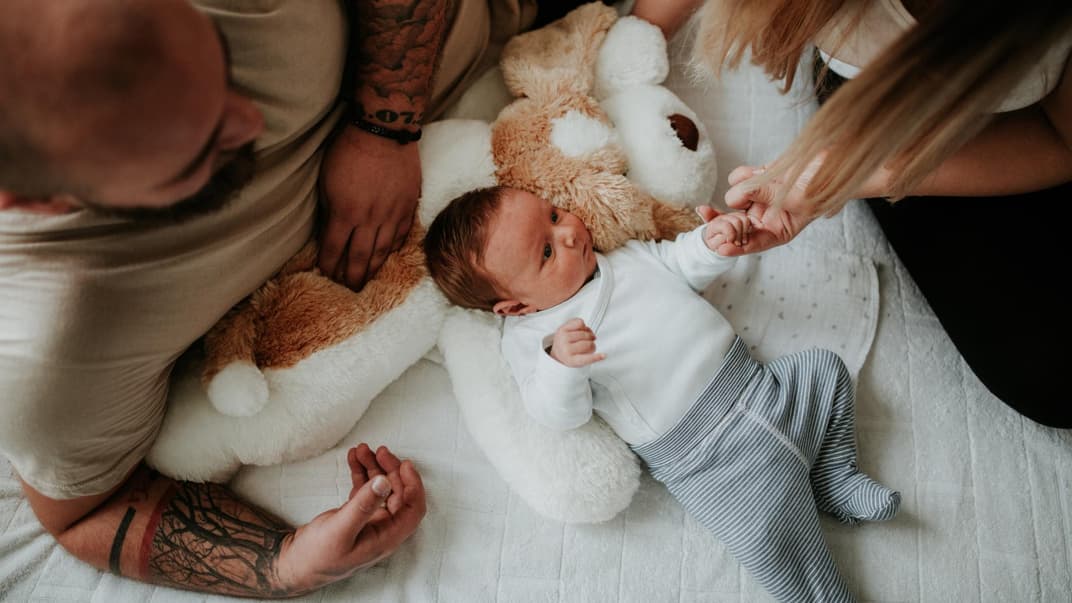 Eltern beugen sich über ihr Baby.