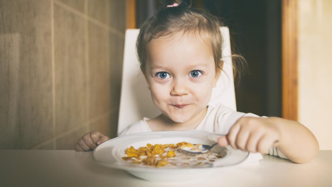 Mädchen freut sich über einen Teller Cornflakes