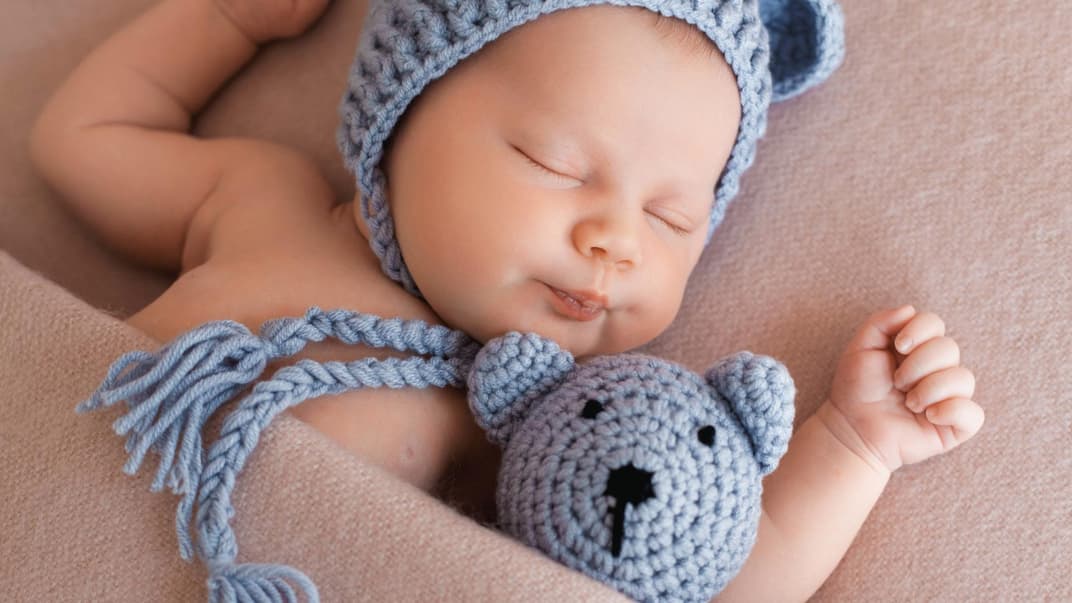 Kleiner Junge schläft mit seinem Teddy im Bett