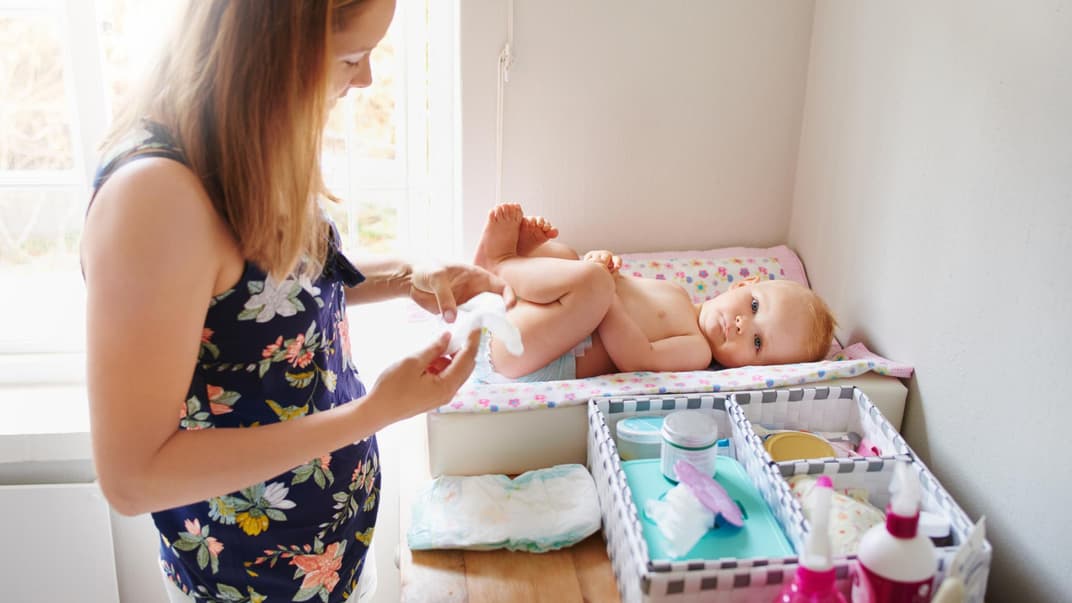 Mama wickelt Baby auf Wickeltisch
