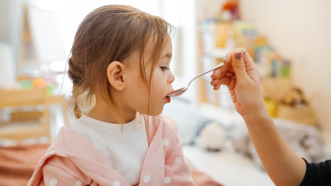 Mädchen bekommt einen Löffel mit Medizin