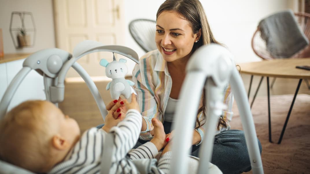 Mama schaukelt Baby in Babywippe