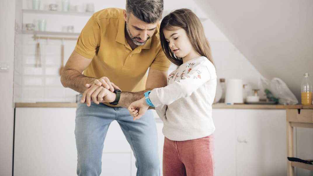 Papa und Tochter checken ihre Smartwatches