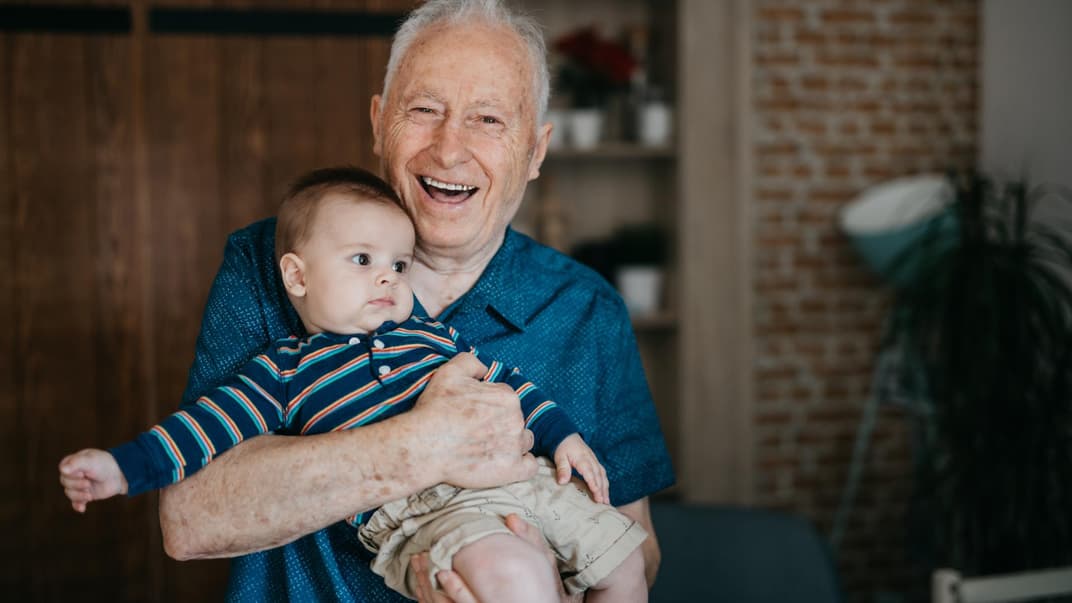 Opa hält Enkel im Arm.