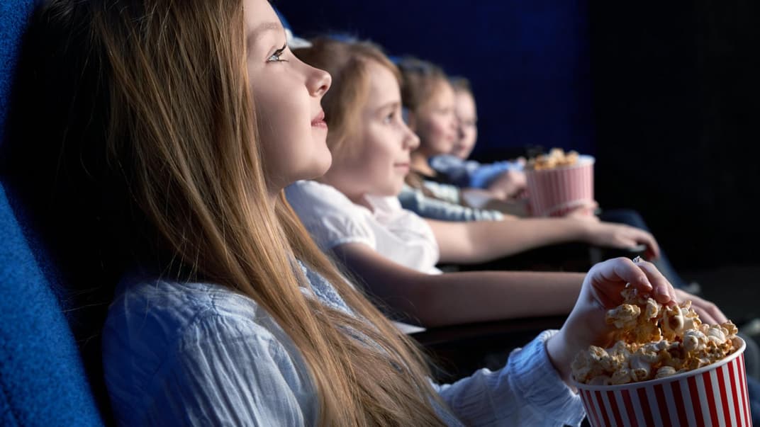 Junge Kinder sitzen im Kino und essen Popcorn. 