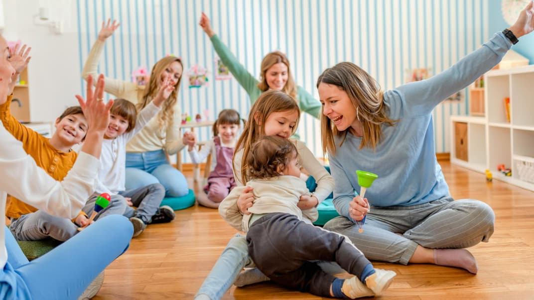 Erzieherinnen spielen mit Kita-Kindern und haben gemeinsam Spaß.