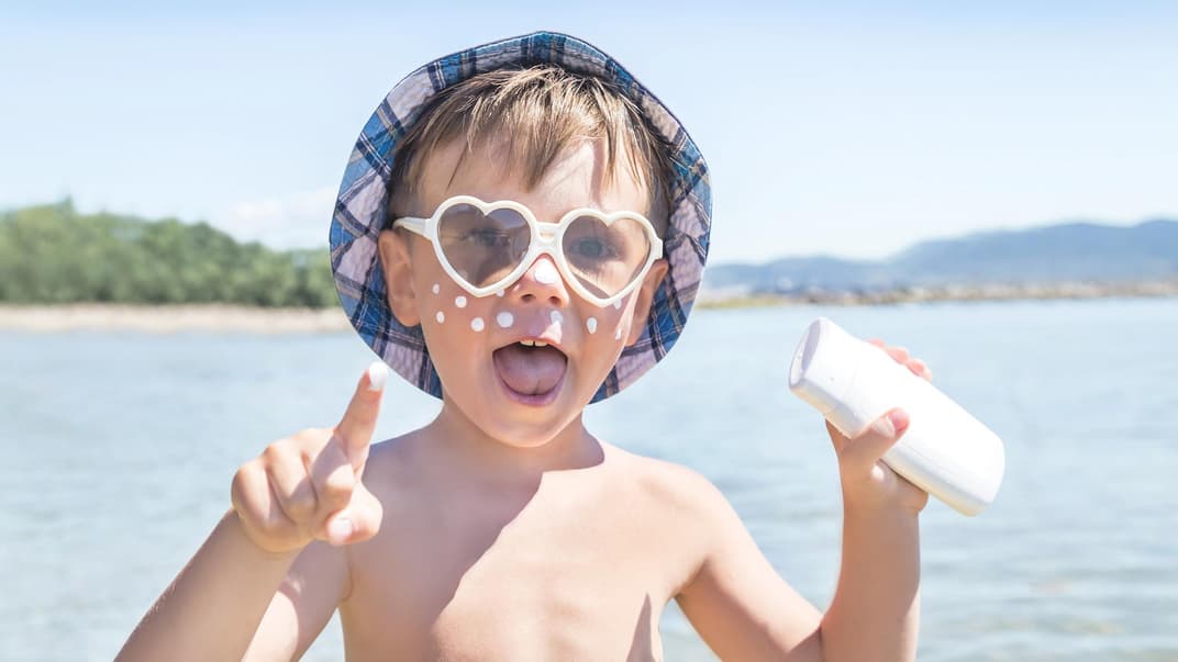 Ein Kind mit Sonnencreme im Gesicht