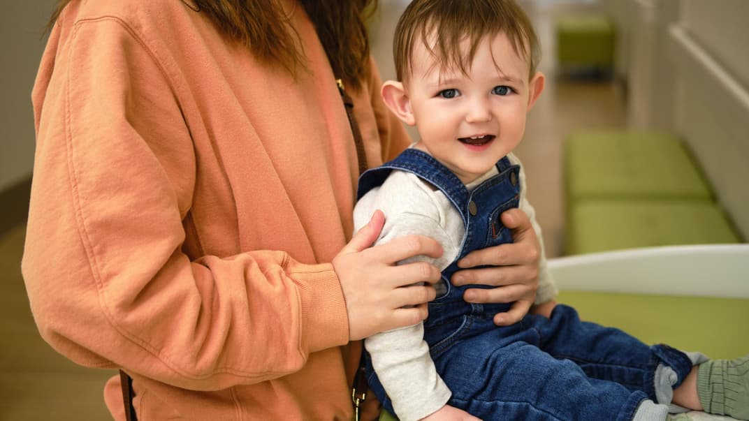 Mutter hält ihr sitzendes Kind auf dem Wickeltisch fest