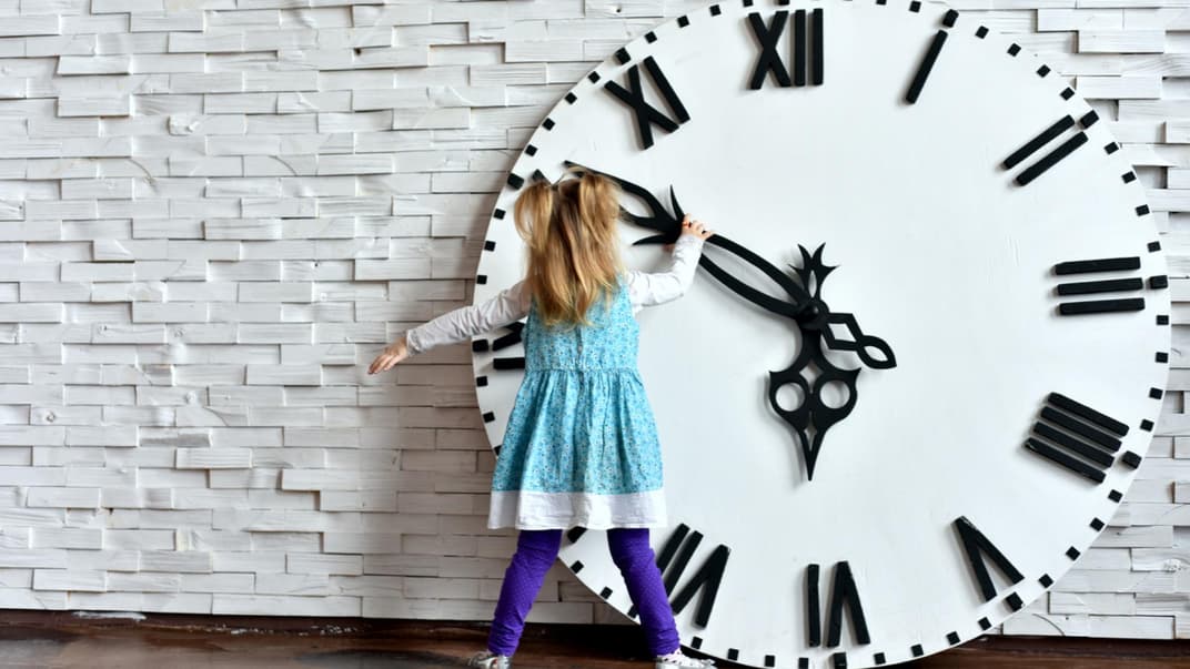 Kleines Mädchen steht vor riesiger Uhr