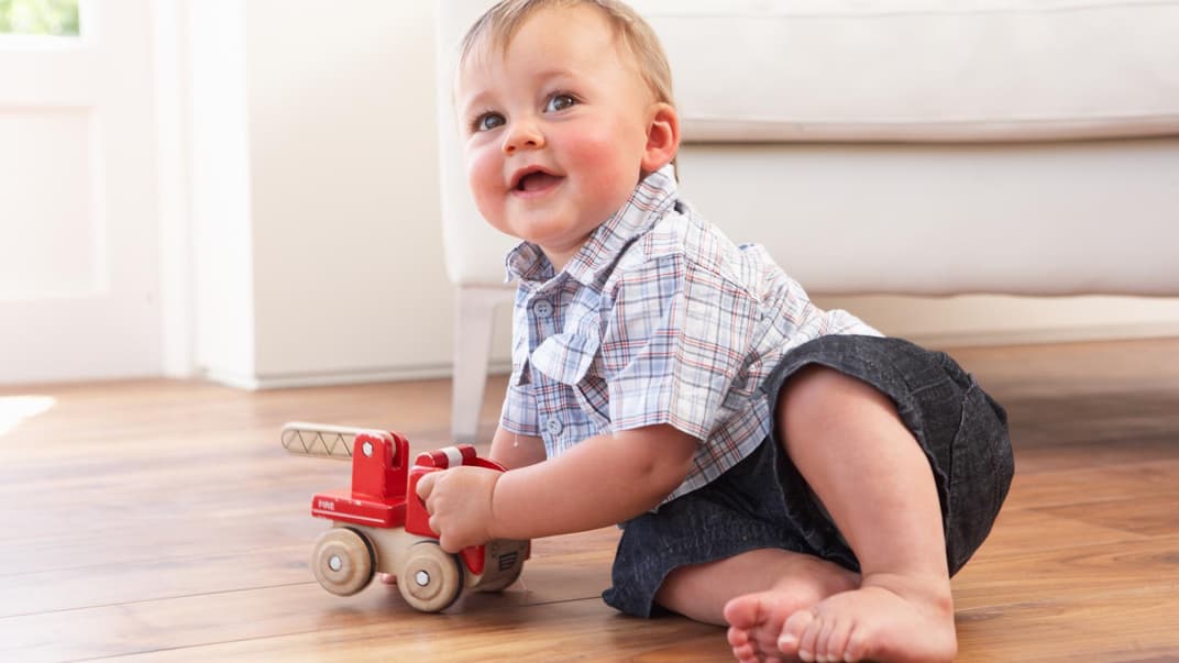 Einjähriger Junge spielt mit Holz-Bagger