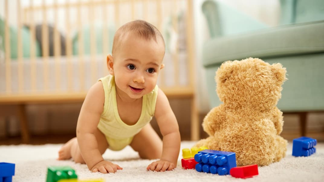 Kleiner Junge krabbelt über den Teppichboden.