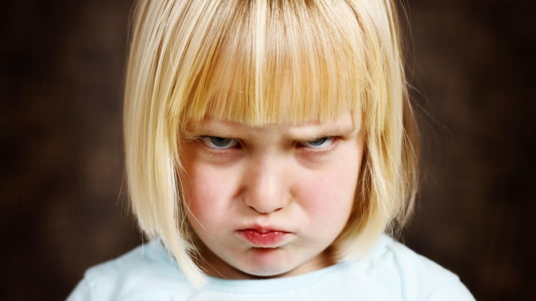 Blondes Mädchen guckt böse.