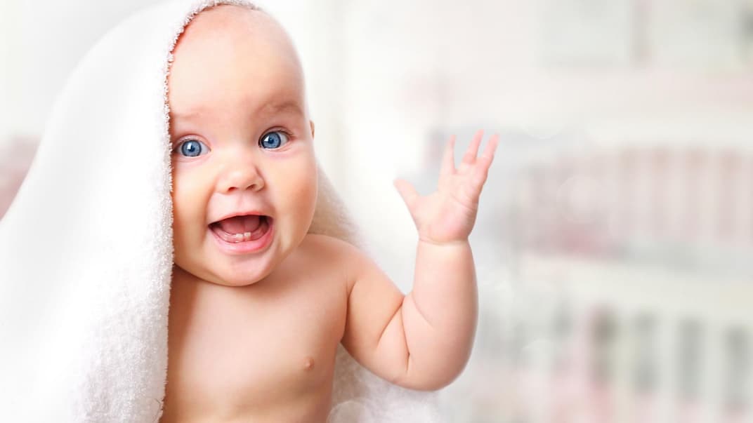 Lachendes Baby unter Handtuch.