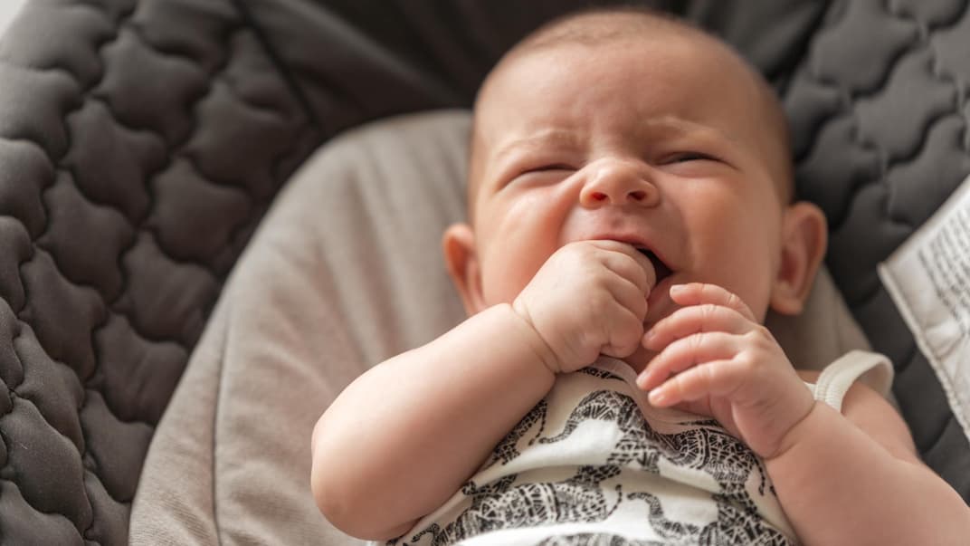 Quengeliges Baby kaut auf seiner Hand