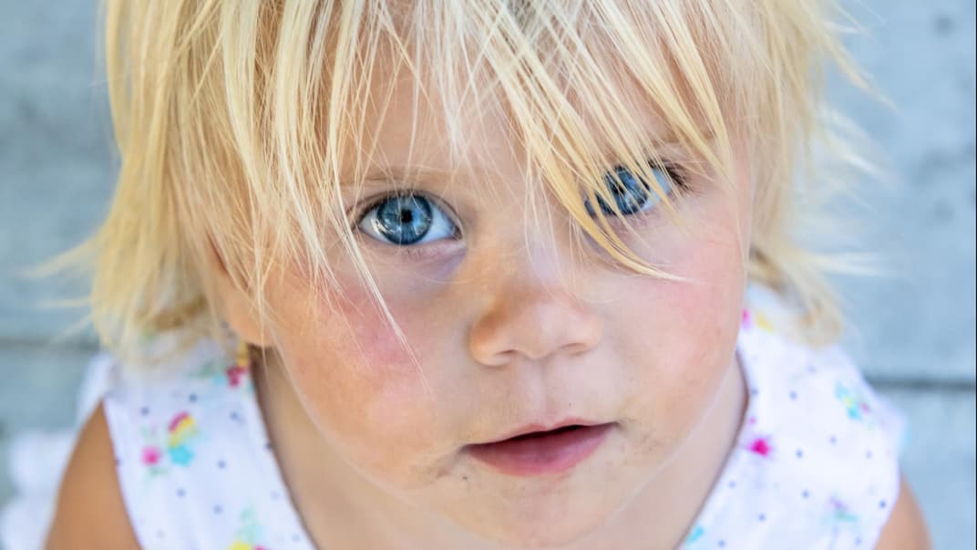 Kleines, blondes Mädchen schaut in die Kamera.