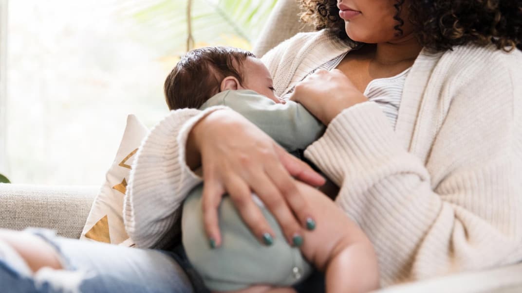 Junge Mutter stillt ihr Baby in einer ihrer liebsten Stillpositionen.