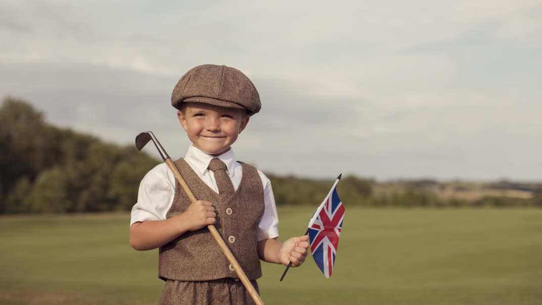 Englischer kleiner Junge in Vintage-Kleidung hält eine britische Flagge in der Hand