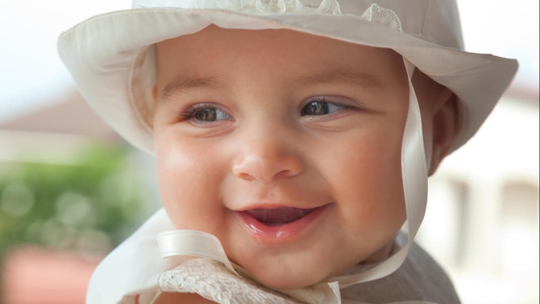 Ein süßes, kleines Mädchen schaut niedlich und lächelnd über ihre rechte Schulter.