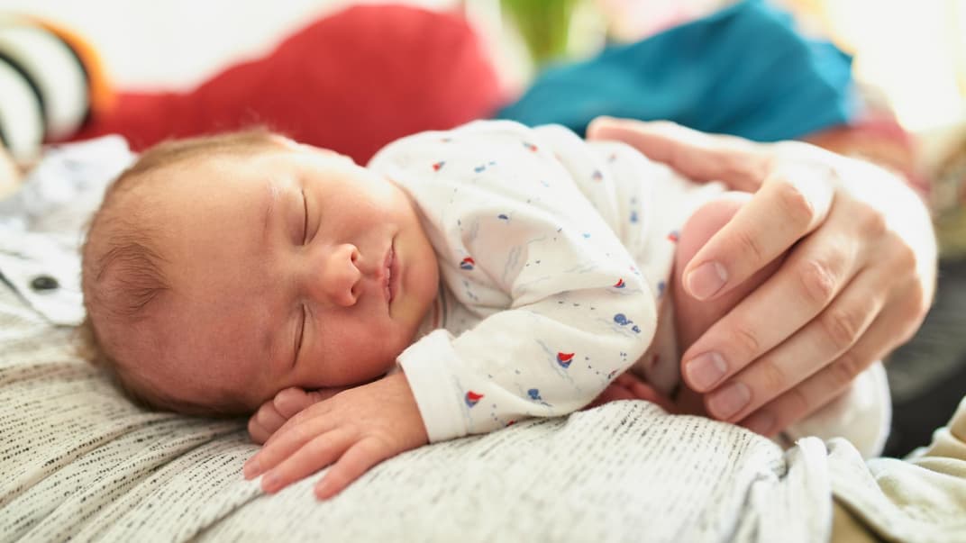 Ein Baby-Mädchen schläft auf der Brust seines Vaters.