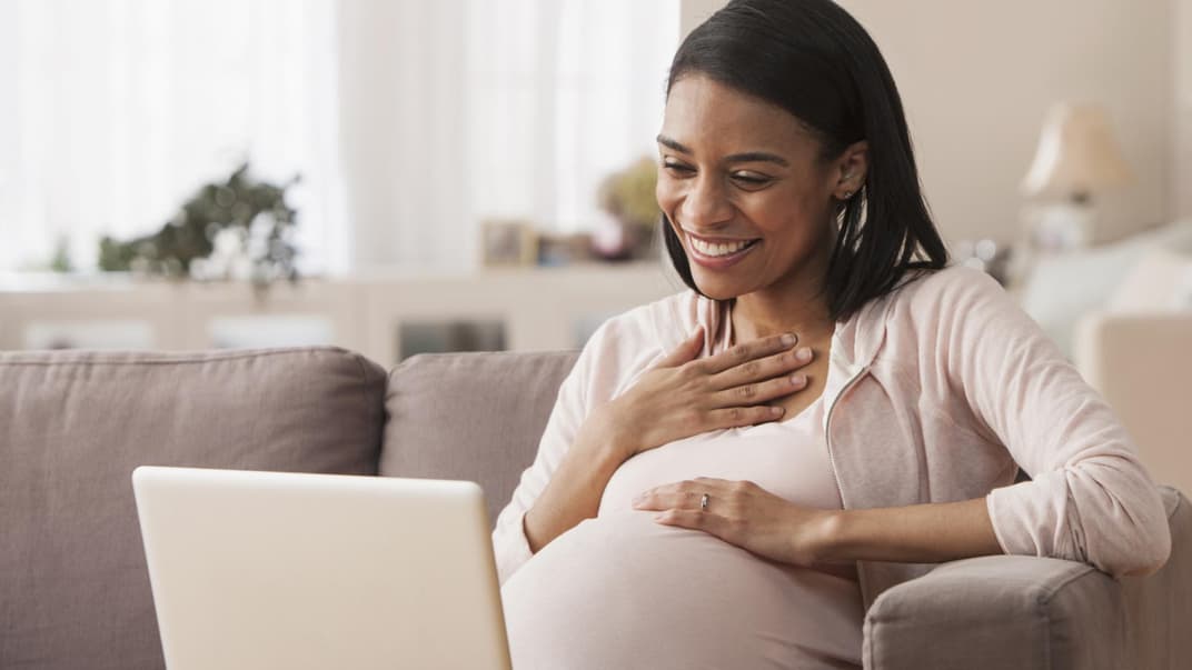Schwangere sitzt am Laptop