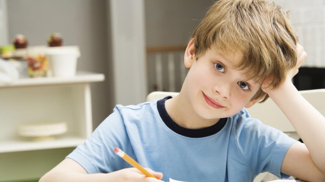 Ein Erstklässler sitz in der Schule am Schreibtisch.