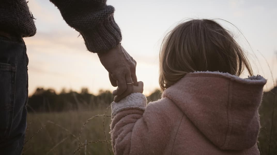 Vater hält die Hand seiner Tochter.