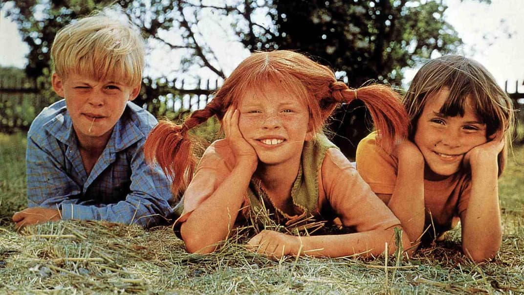 Thomas, Pippi Langstrumpf und Annika liegen auf dem Rasen und schauen in die Kamera.