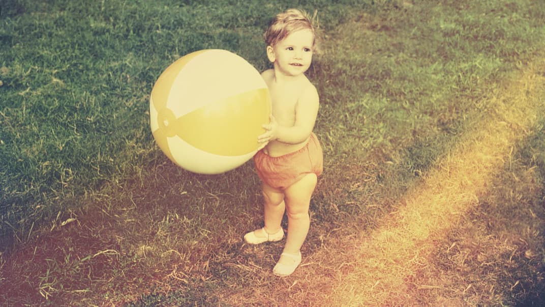 Kleinkind mit Wasserball im Garten