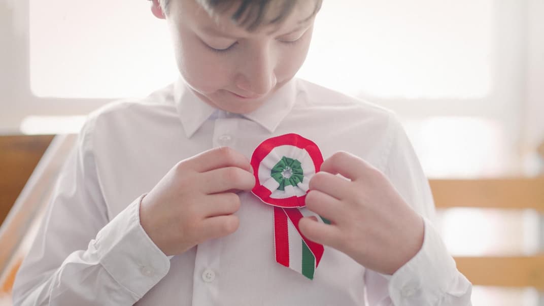 Junge steckt sich eine ungarische Flagge ans Hemd.