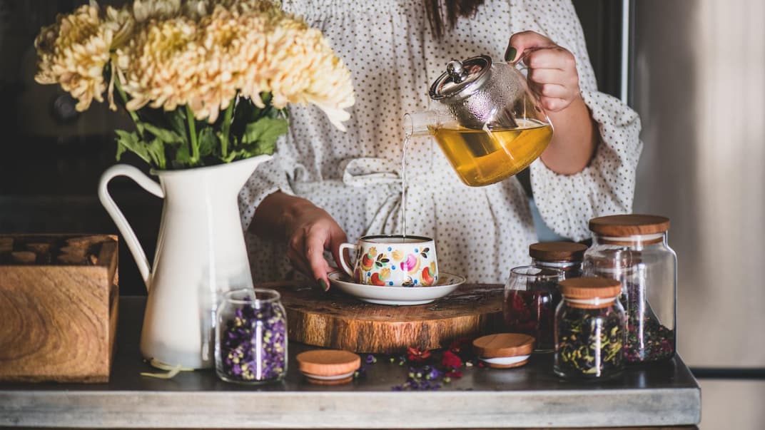 Frau schenkt sich Kräutertee ein.